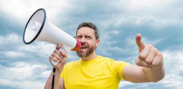 Homme en chemise jaune crier dans le haut-parleur sur la communication de fond de ciel