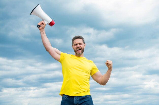 Homme en chemise jaune avec mégaphone sur fond de ciel nouvelles chaudes