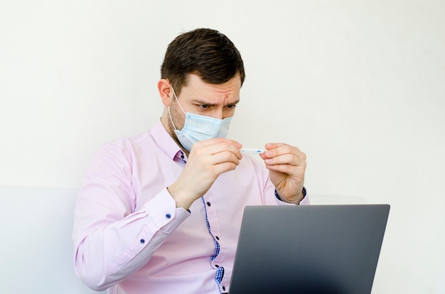 Un homme en chemise avec un masque mesure la température