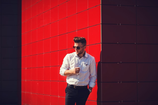 Homme en chemise sur un mur rouge