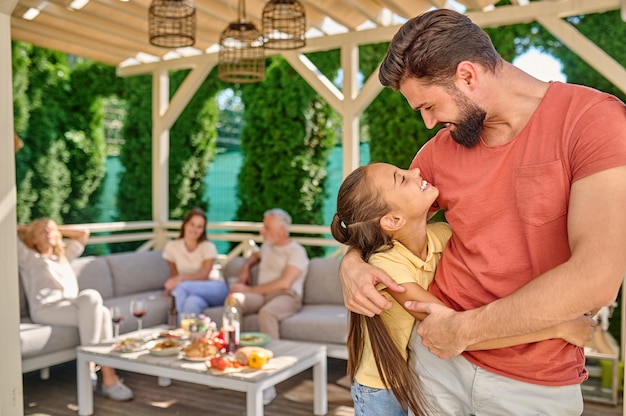 Un homme en chemise rouge debout avec sa fille