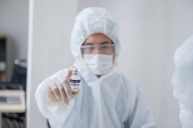 Homme chercheur en ppe médical montrant une bouteille de vaccin efficace contre Covid-19 en laboratoire
