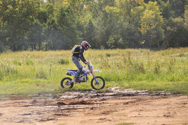 Homme à cheval sur pitbike sur route de campagne sale