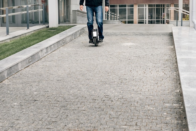 Homme à cheval rapide sur monocycle électrique sur la rue de la ville.