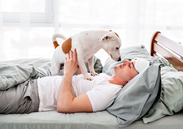 Homme avec chien dans le lit