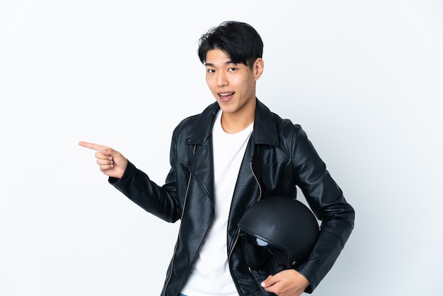 Homme chinois avec un casque de moto isolé sur fond blanc doigt pointé sur le côté et présentant un produit
