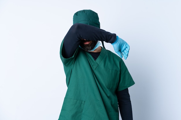 Homme chirurgien en uniforme vert sur un mur isolé couvrant les yeux par les mains