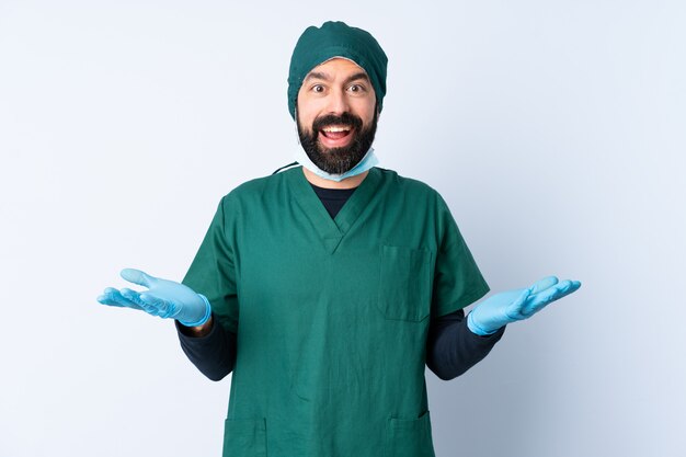 Homme chirurgien en uniforme vert sur un mur isolé avec une expression faciale choquée