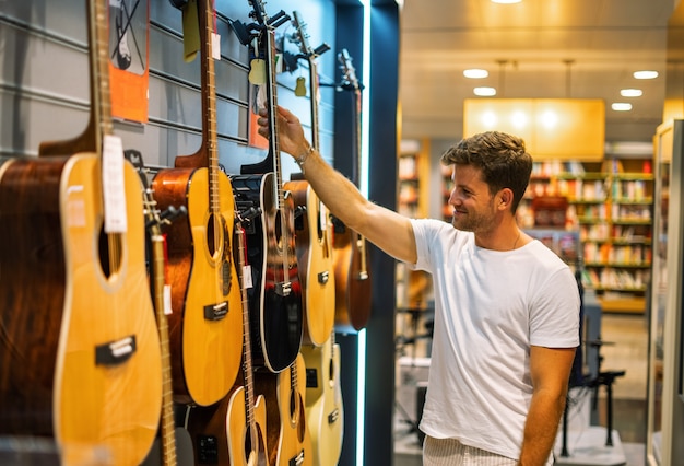 Homme choisissant la guitare dans la boutique