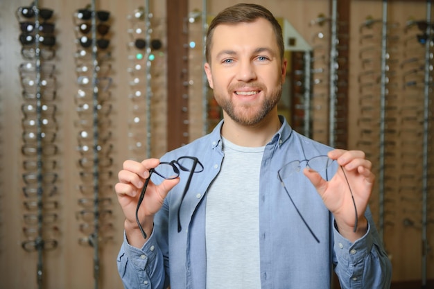 Photo l'homme choisit des lunettes dans un magasin d'optique