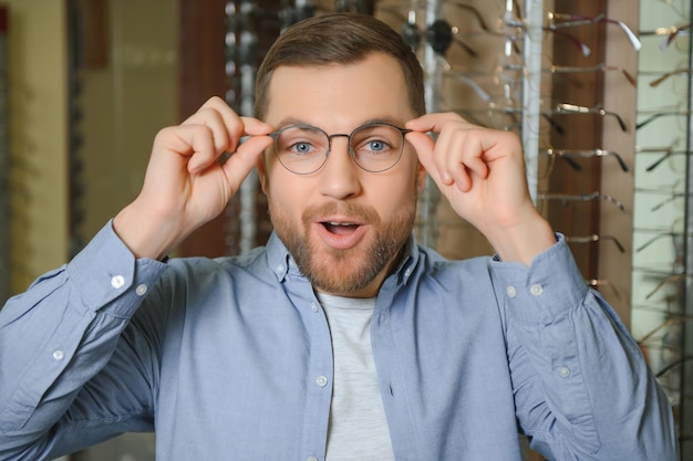 L'homme choisit des lunettes dans un magasin d'optique