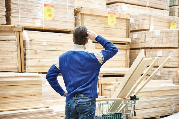 L'homme choisit des planches pour la construction du magasin