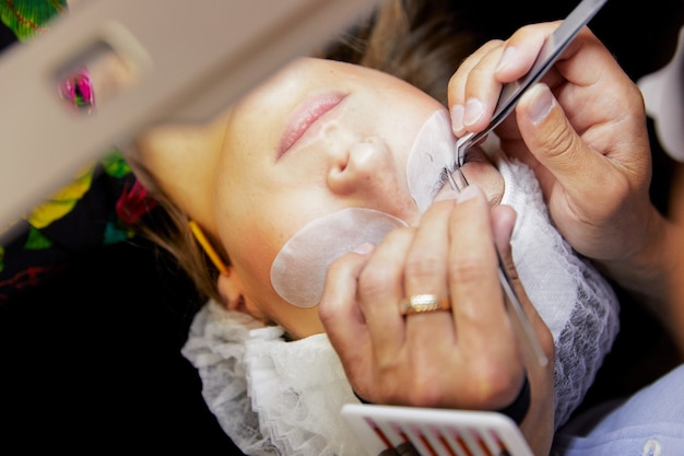 homme cils femme avec des dispositifs spéciaux dans un salon de beauté