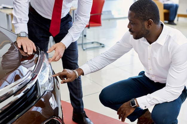 Photo l'homme client noir pose des questions sur les phares de la voiture chez le concessionnaire