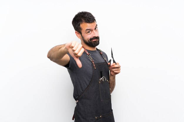 Photo homme coiffeur dans un tablier montrant le pouce vers le bas avec une expression négative