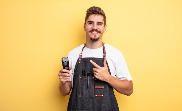 Homme de coiffeur hipster souriant joyeusement, se sentant heureux et pointant vers le côté