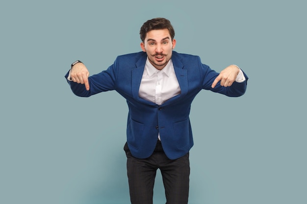 Homme en colère debout pointant vers le bas donnant la commande en regardant la caméra avec une expression sérieuse