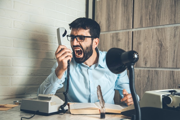 Homme en colère parle téléphone avec livre sur 24