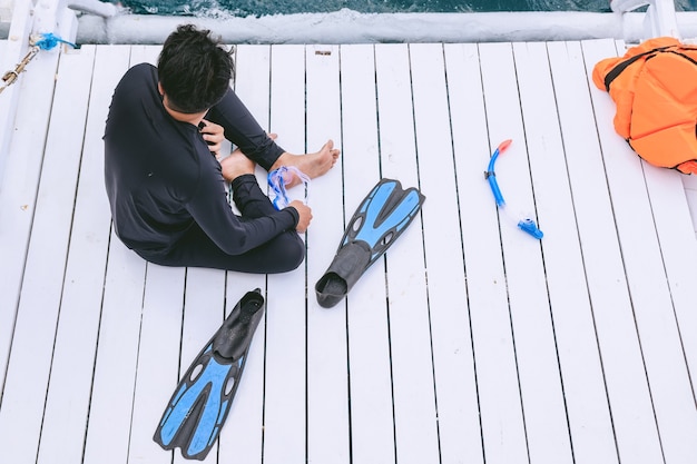 Un homme en combinaison de plongée assis et se reposant sur le bateau après la plongée