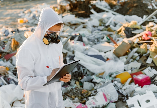 Homme en combinaison à la poubelle. Fais des recherches. Concept d'écologie, pollution de l'environnement.