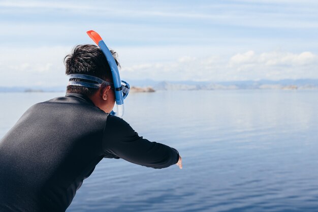 Homme en combinaison prêt à sauter dans la mer pour la plongée en apnée