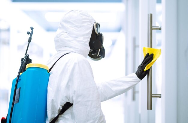 Photo un homme en combinaison de protection contre les matières dangereuses lave le mobilier de bureau pour empêcher la propagation du coronavirus