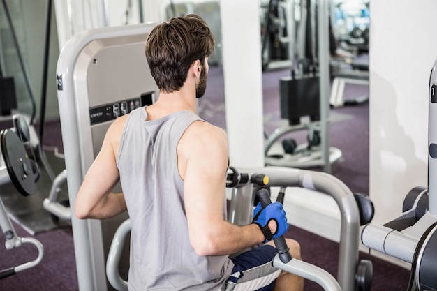 Homme concentré à l&#39;aide de poids machine pour les bras à la gym