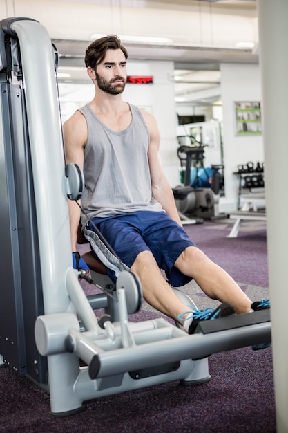 Homme concentré à l&#39;aide de poids machine pour les jambes à la gym