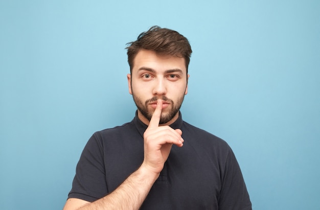 L'homme concentré est isolé sur jaune et montre un signe de silence