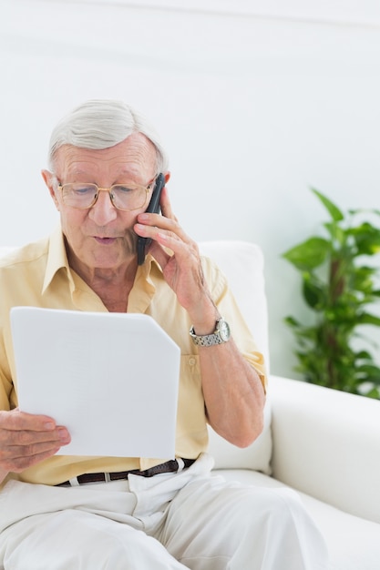 Homme concentré homme lisant des papiers sur le téléphone