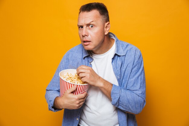 Homme concentré mangeant du pop corn regarder le film à la recherche.