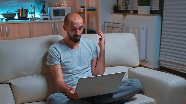 Homme concentré travaillant sur un ordinateur portable pendant un appel vidéo professionnel