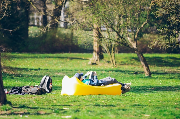 Homme de concept de lecture de livre dans le parc de la ville sur un matelas gonflable