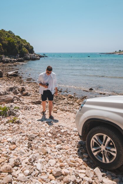 Homme de concept de voyage de voiture à la plage d'été regardant la mer