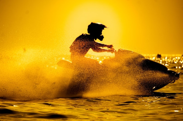 Homme conduire jet ski au coucher du soleil