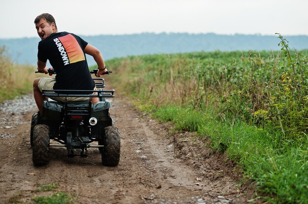 Homme conduisant un quad ATV à quatre roues.