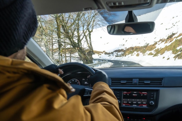 Homme conduisant une voiture avec de la neige sur la montagne vue de l'intérieur