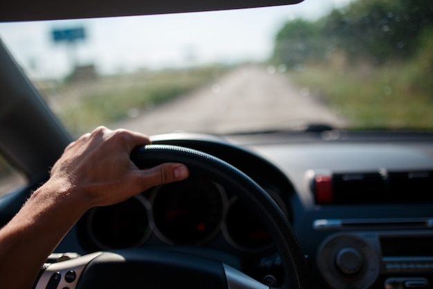 Un homme conduisant une voiture, se concentre sur la main gauche tenue sur le volant.