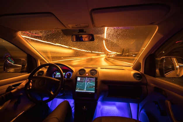 L'homme conduit avec un gps sur la route de nuit. Vue de l'intérieur. Grand angle