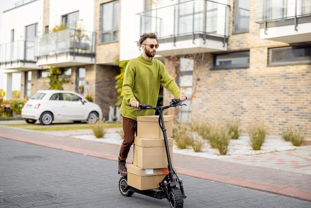 Un homme conduit un scooter électrique avec des emballages en carton