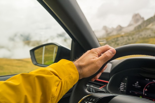 Un homme conduit une voiture sur une autoroute contre des Alpes italiennes géantes