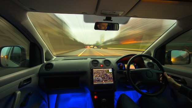 L'homme conduit une voiture sur l'autoroute. Vue de l'intérieur. Circulation à gauche