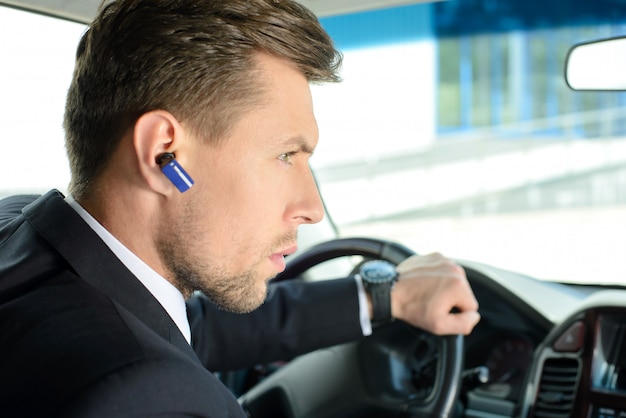 Un homme conduit une voiture et parle en Bluetooth.