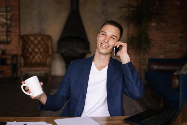 Homme confiant assis sur le bureau prenant une pause de travailler avec l'électronique