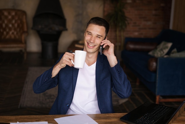 Homme confiant assis sur le bureau prenant une pause de travailler avec l'électronique