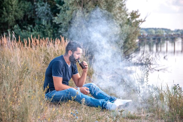 Un homme confiant libère un nuage de vapeur. Se débarrasser de la dépendance à la nicotine.