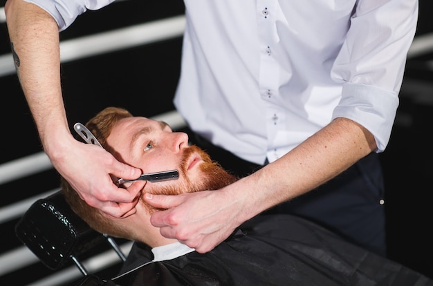 Homme confiant visite coiffeur en salon de coiffure.