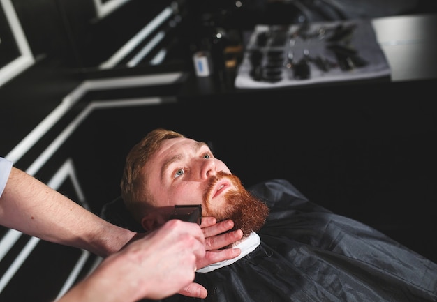 Homme confiant visite coiffeur en salon de coiffure.