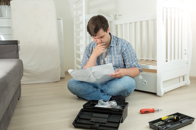 Homme confus d'assembler le manuel de lecture de meubles