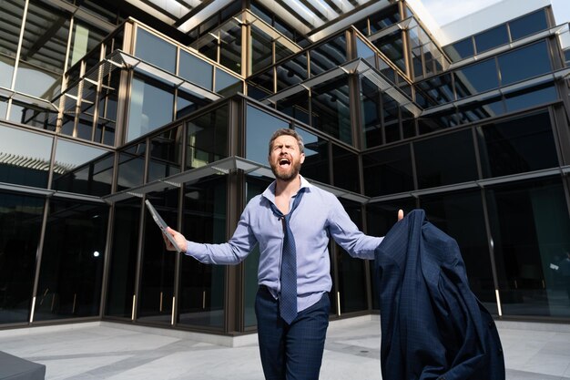 Homme confus frustré par un problème commercial criant avec une veste et un ordinateur portable frustration en plein air